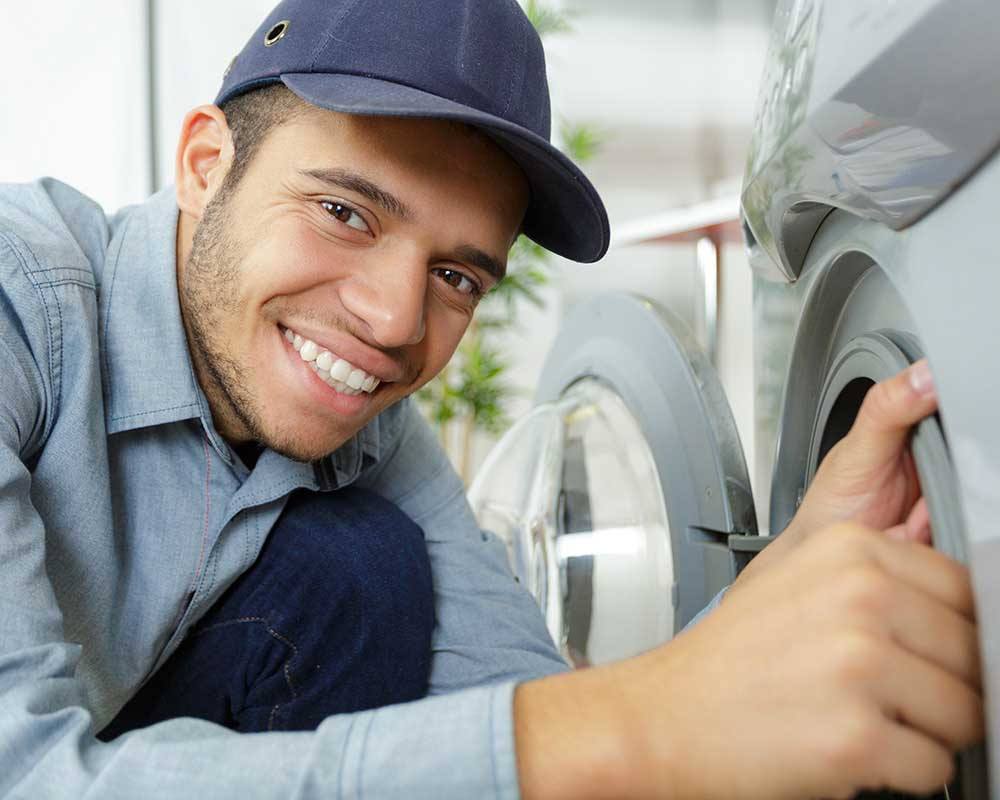 smiling hispanic technician working on washing machine